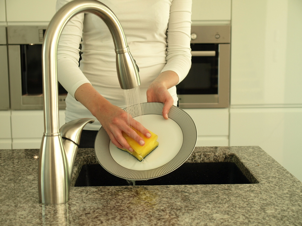 woman's hands washing a delicate china dish under running water in sink